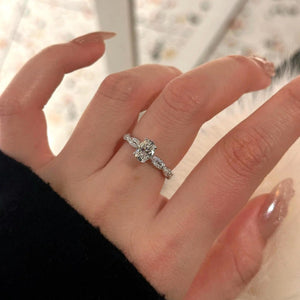 Sterling silver oval moissanite ring with diamond accents on band.