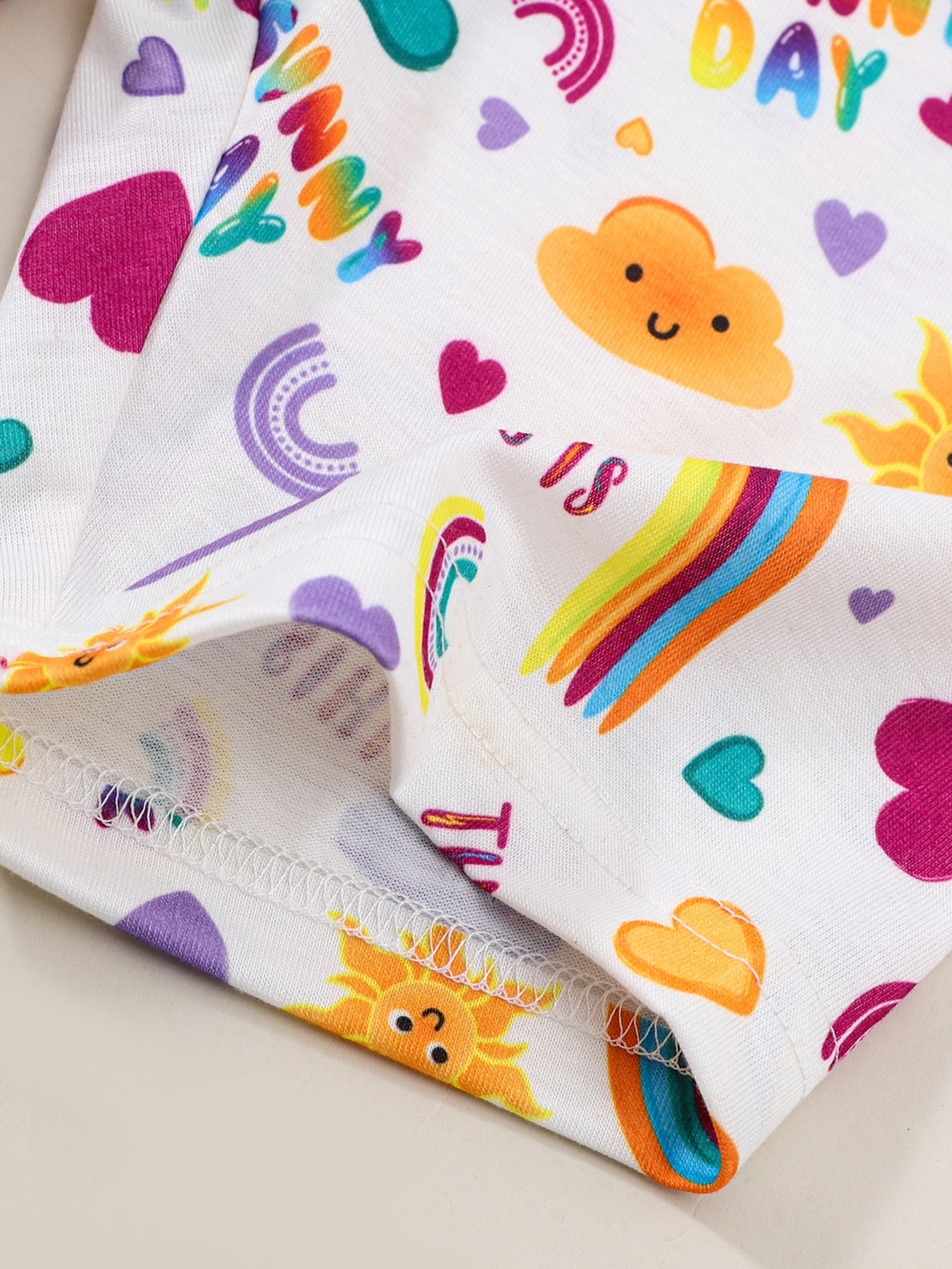 Girls' white graphic tee and shorts set with rainbow, sun, cloud, and heart prints.