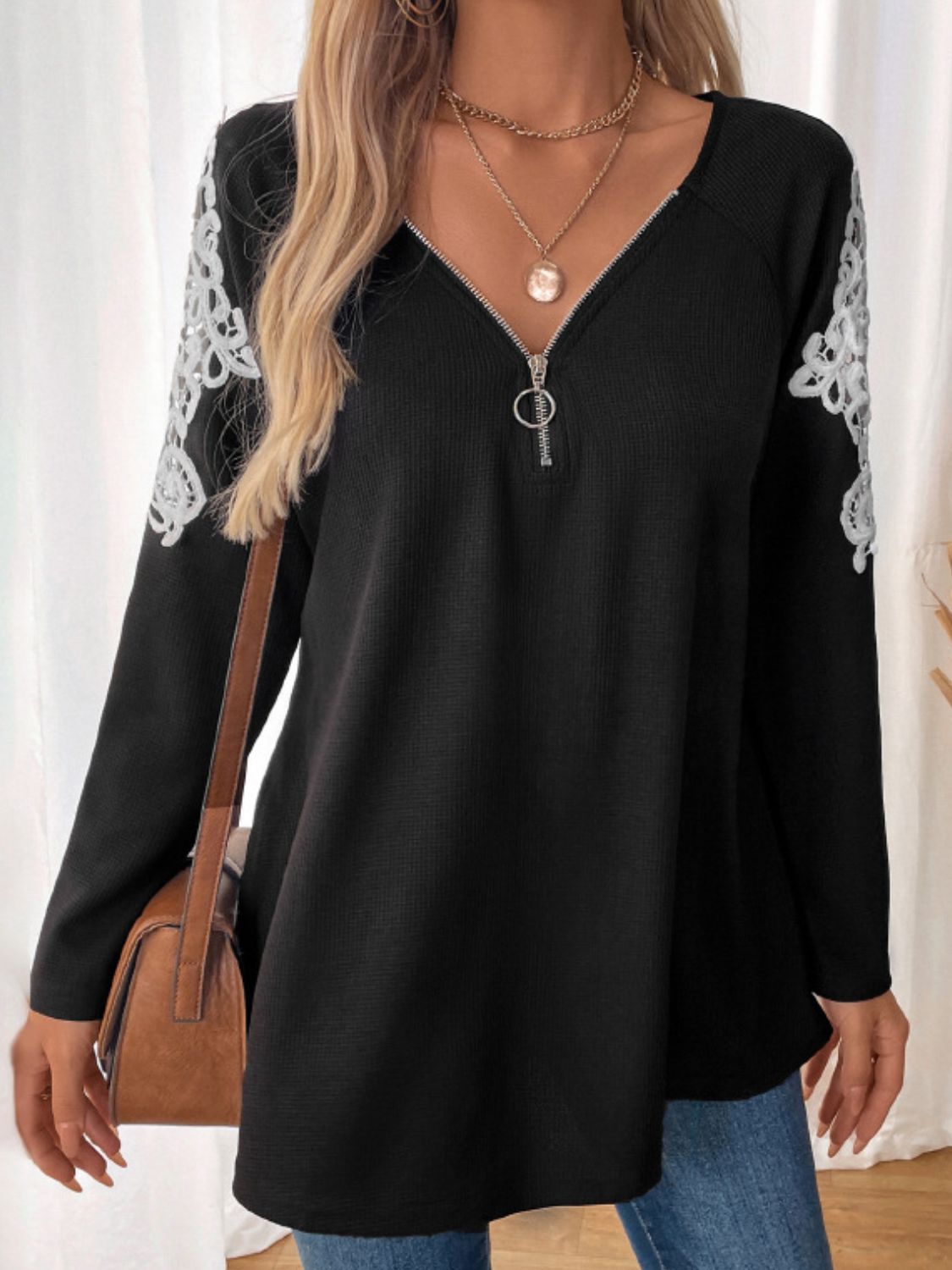 Black ribbed knit zip-front top with white lace trim on sleeves.