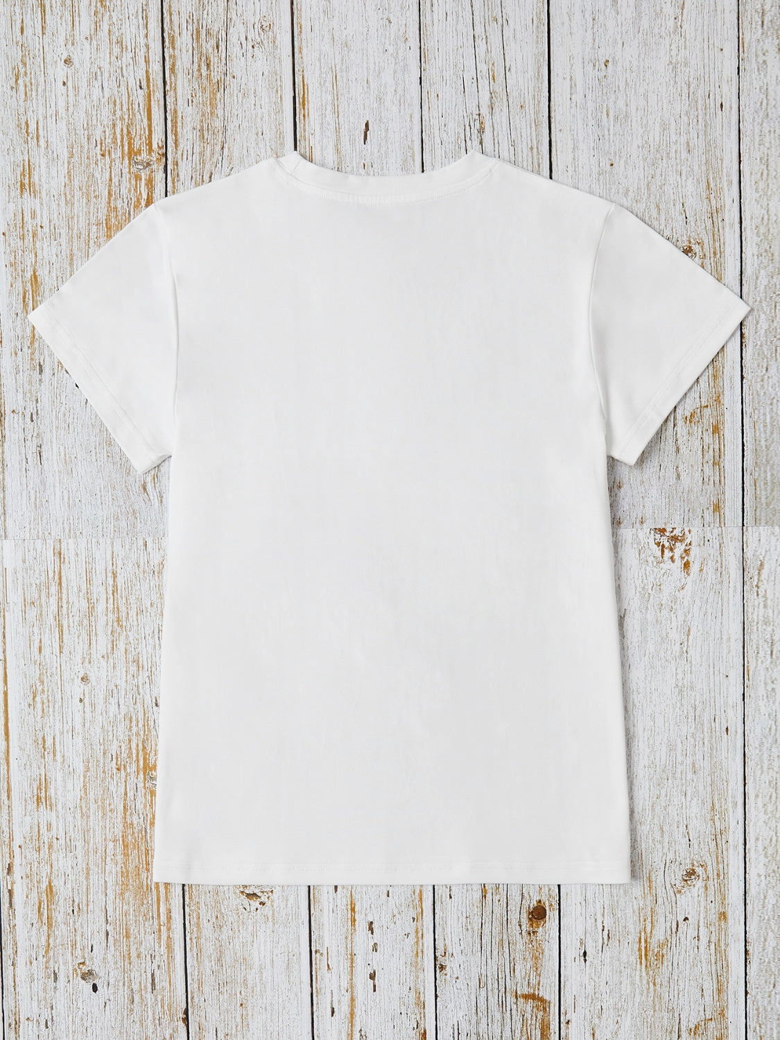 White t-shirt with short sleeves and crew neck, featuring iridescent heart and cross appliqué detail.