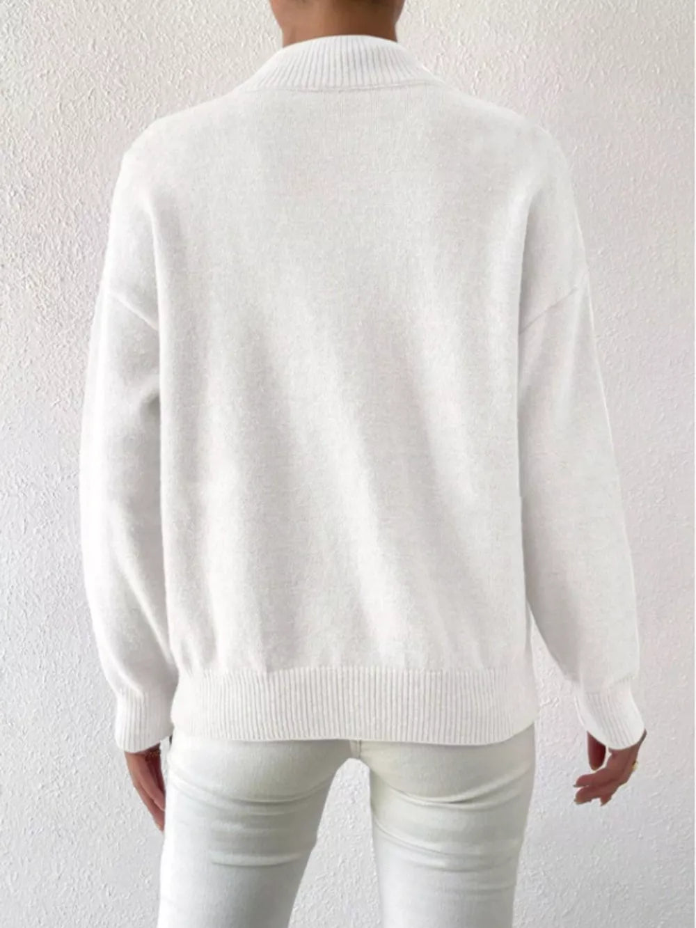 White mock neck knit sweater with dropped shoulders and ribbed cuffs and hem.