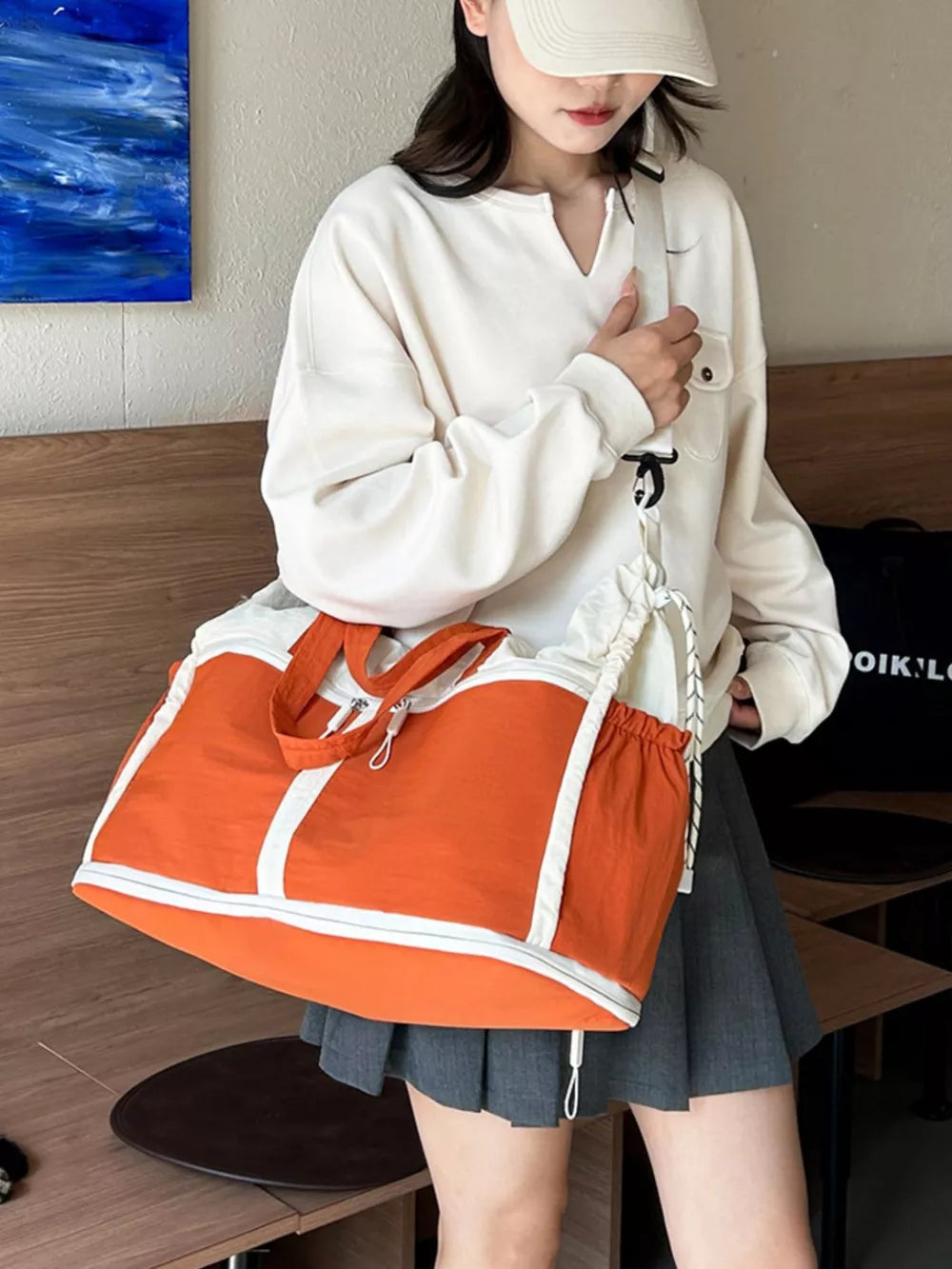 Vibrant color-block travel bag with orange and white panels, drawstring closure, and dual handles.