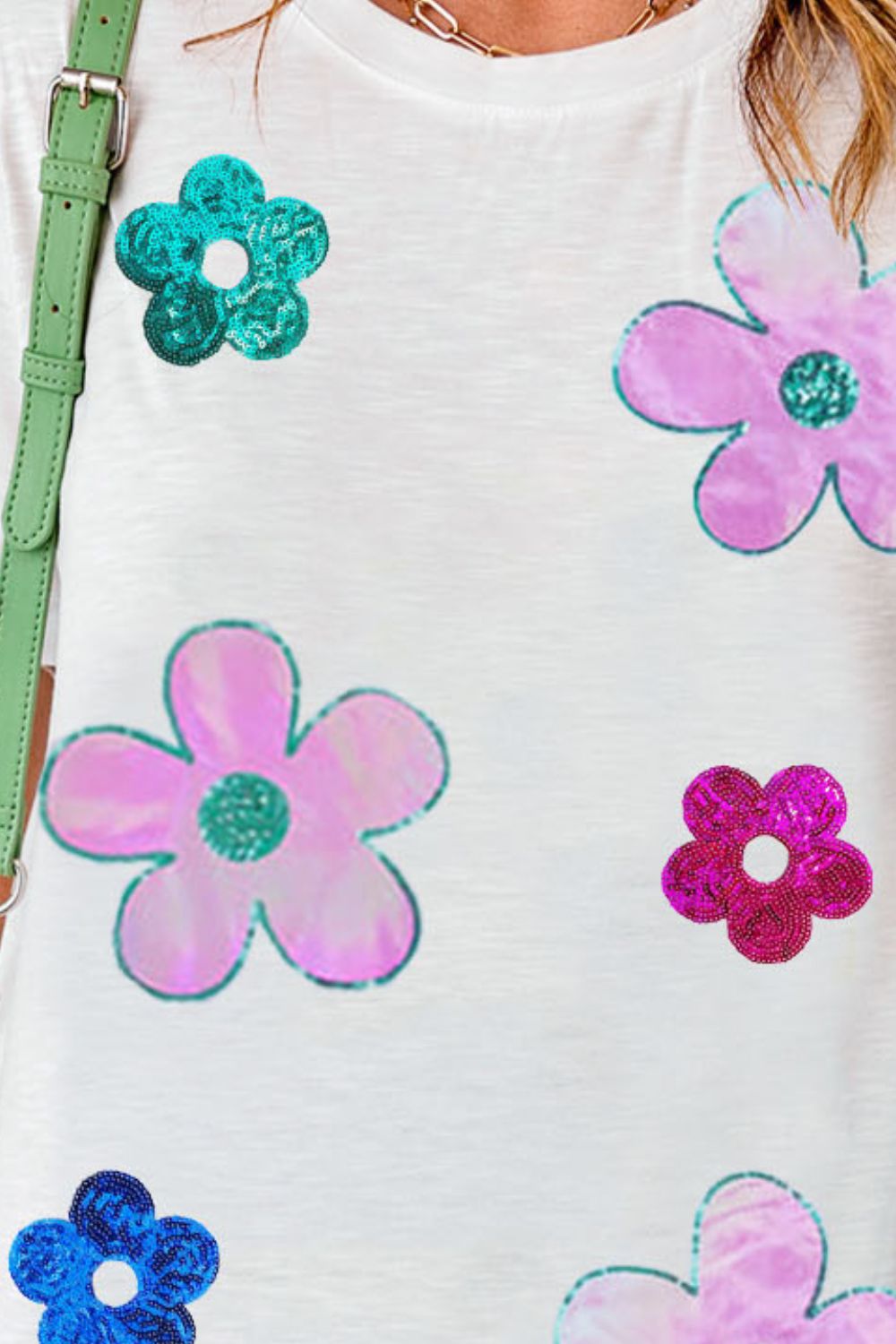 White tee with sequin floral appliqués in pink, teal, and magenta.