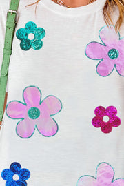 White tee with sequin floral appliqués in pink, teal, and magenta.