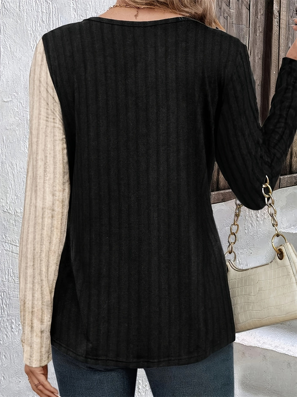 Split-panel ribbed henley top in black with a beige sleeve, featuring a crew neck and long sleeves.