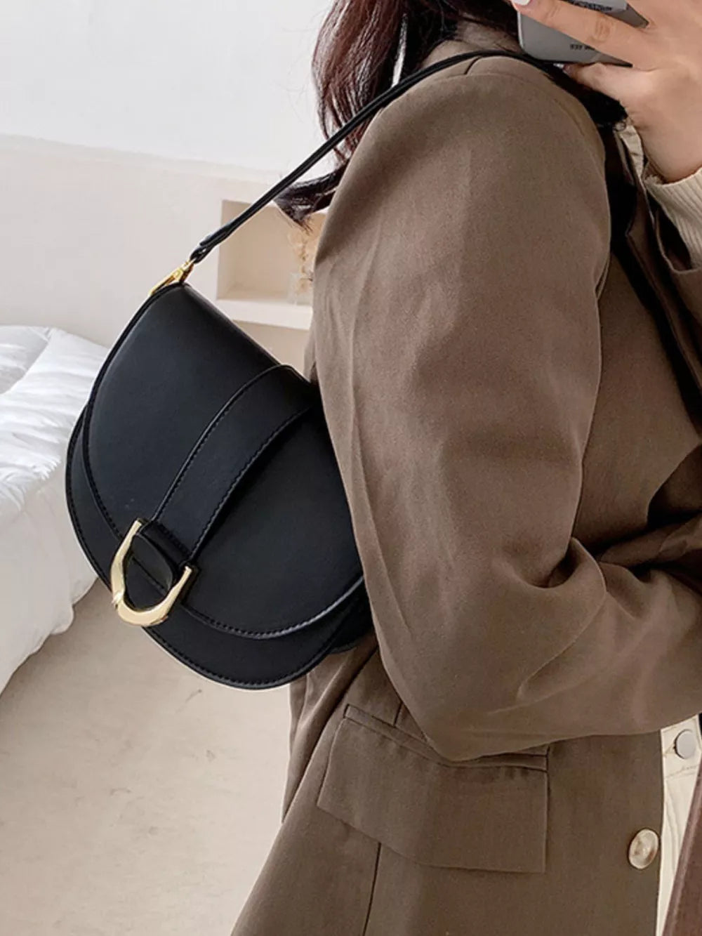 Chic black semi-circular flap crossbody bag with gold buckle detail.