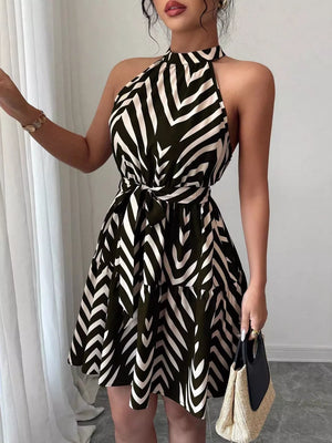 Chic halter neck dress with tie waist and tiered ruffle skirt in a black and white chevron pattern.