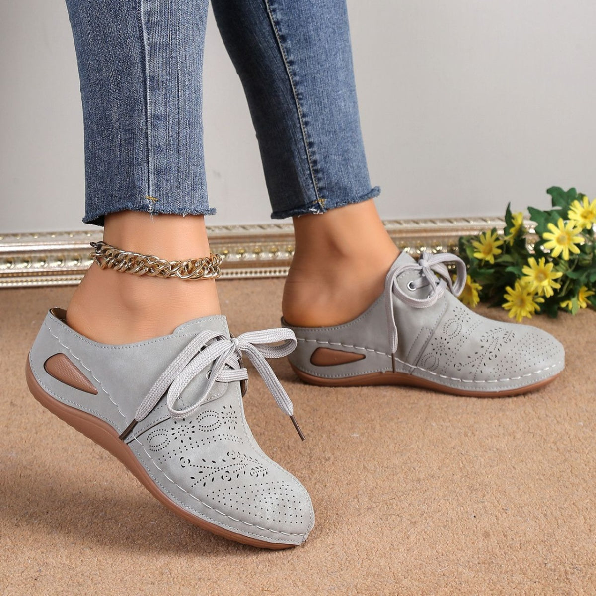 Light gray perforated slip-on mules with lace-up detail and cut-out sides.