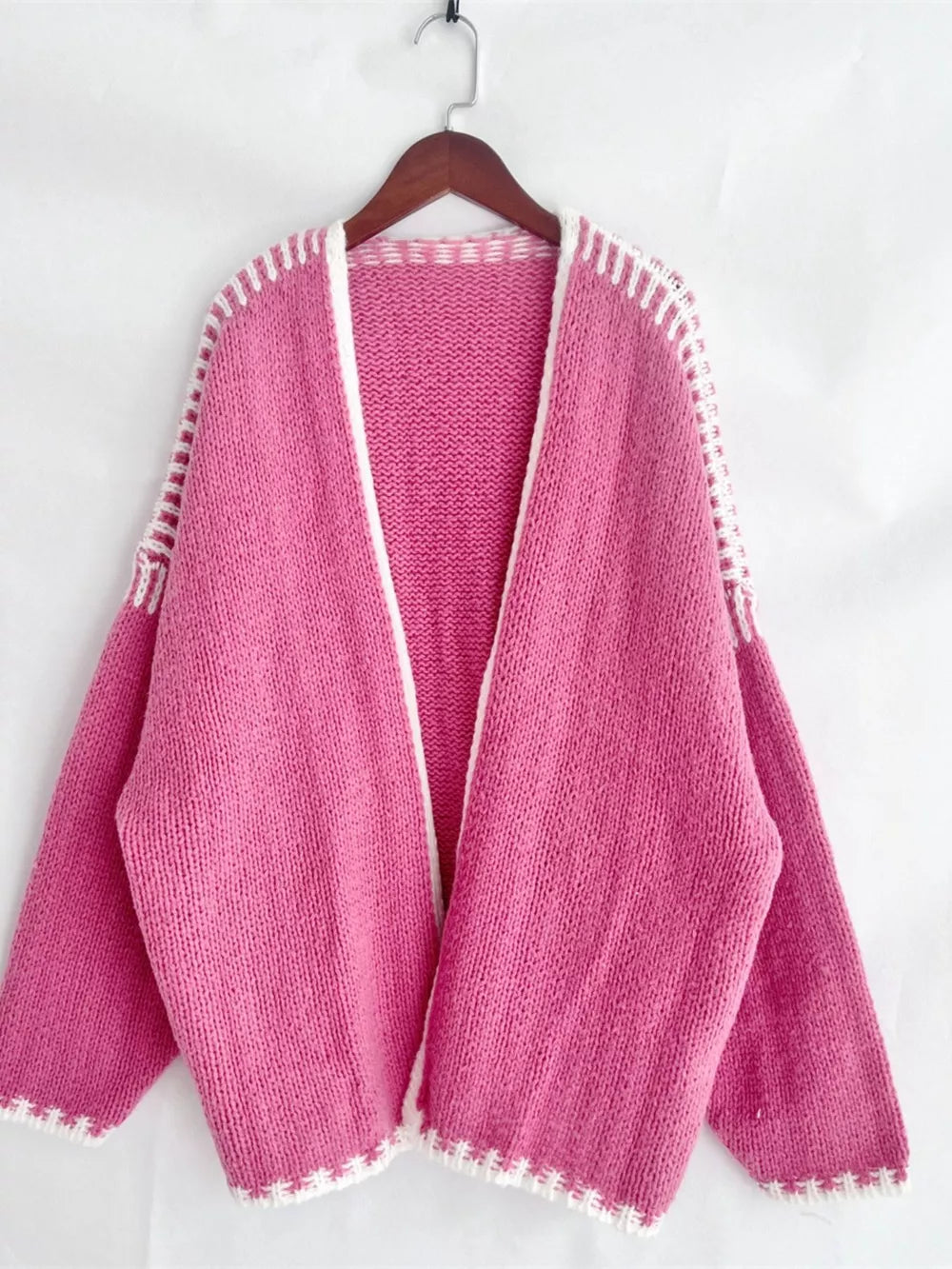 Oversized hot pink knit cardigan with white contrast trim and open front.