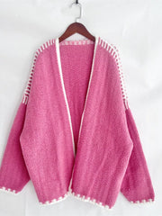 Oversized hot pink knit cardigan with white contrast trim and open front.