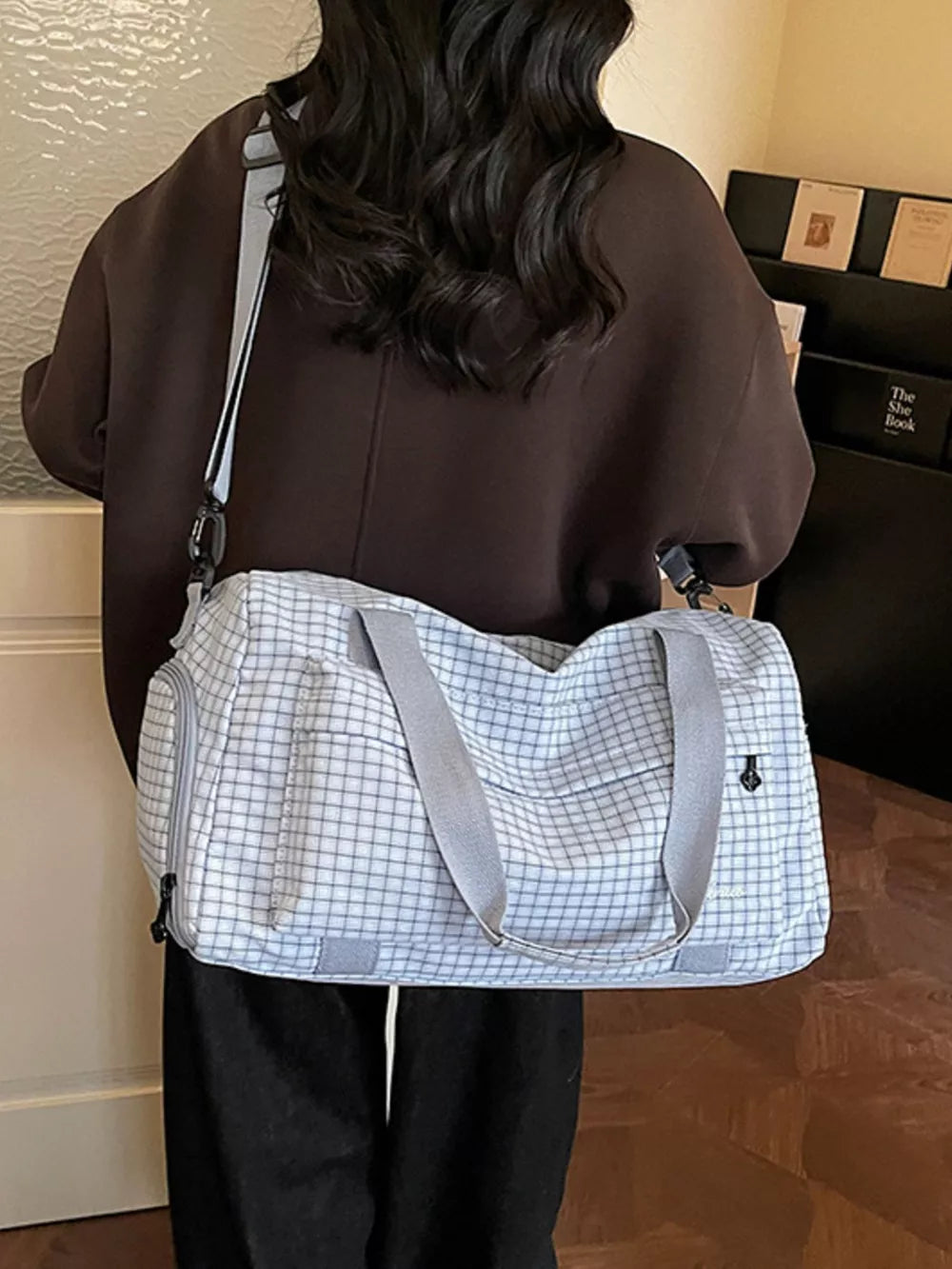 Elegant plaid travel bag with grey straps and multiple pockets.