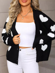 Black knit cardigan with white heart pattern, button-up front, and long sleeves.