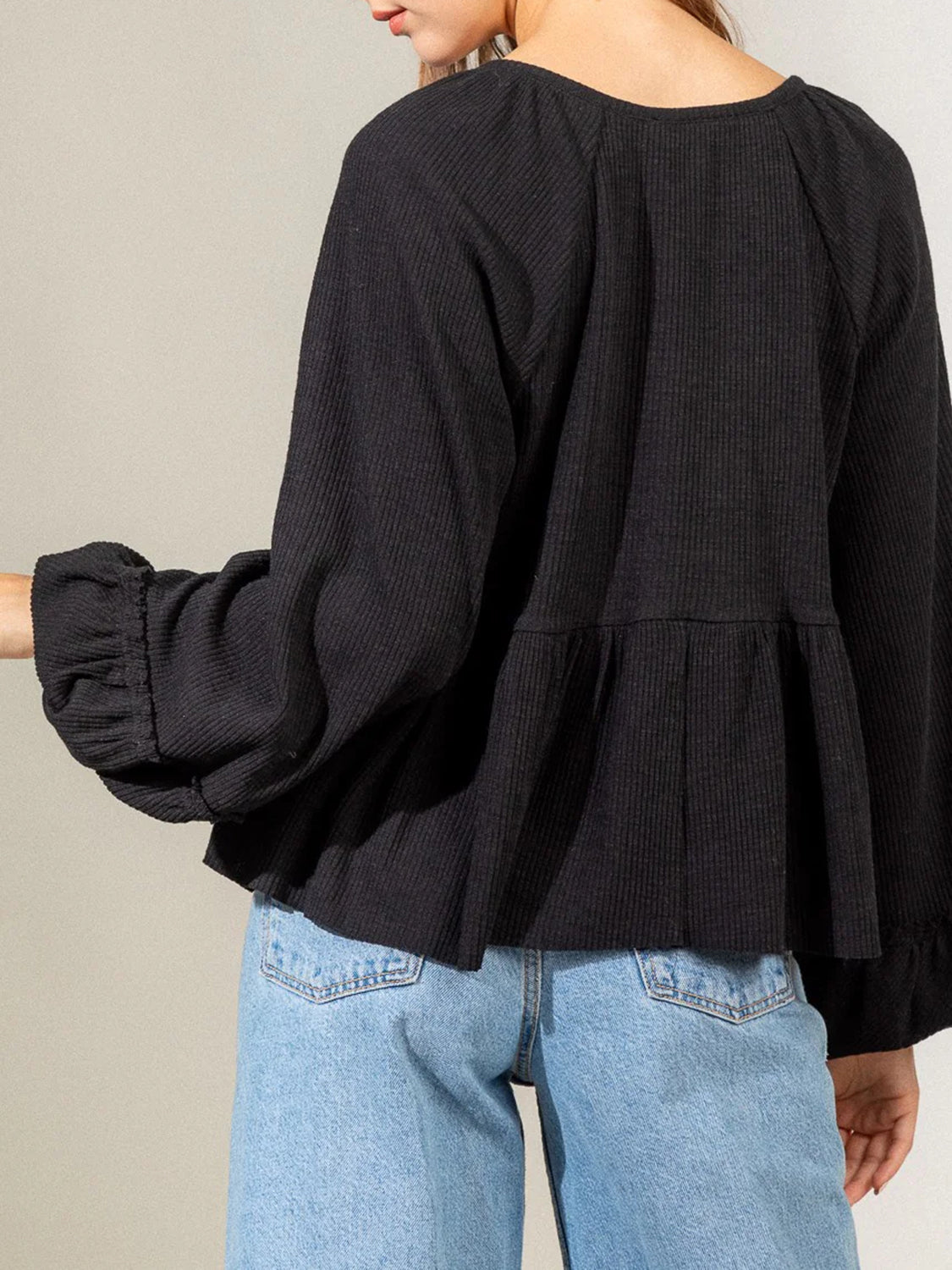 Black ribbed peplum blouse with ruffled cuffs and balloon sleeves.