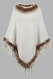 Ivory textured knit poncho with faux fur trim and fringe details.
