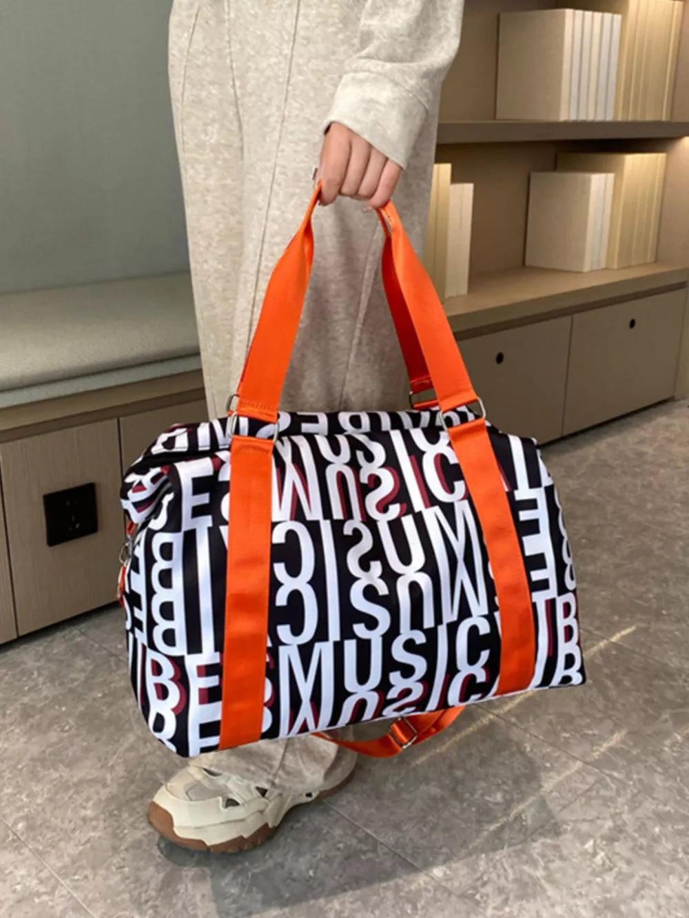 Chic travel bag with black and white letter print and orange straps.