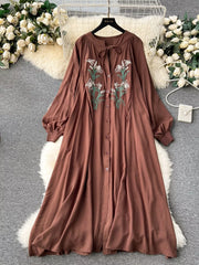Brown cotton maxi dress with embroidered floral detail and tie neck.