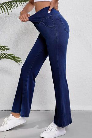 Medium wash denim flare trousers with a crossover waist detail.