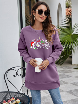 Purple graphic tunic sweatshirt with "Don't Stop Believing" holiday print, crew neck, long sleeves, and side pockets.