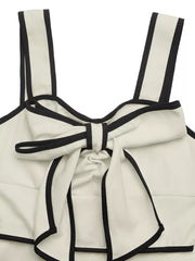 Beige A-line midi dress with black trim and bow detail at neckline