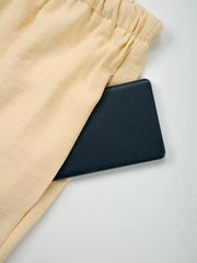 Pastel Yellow maternity pants with drawstring waist and a pocket holding a black wallet.