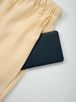 Pastel Yellow maternity pants with drawstring waist and a pocket holding a black wallet.