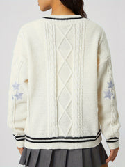 White cable knit cardigan with diamond pattern, star details on sleeves, and striped trim.