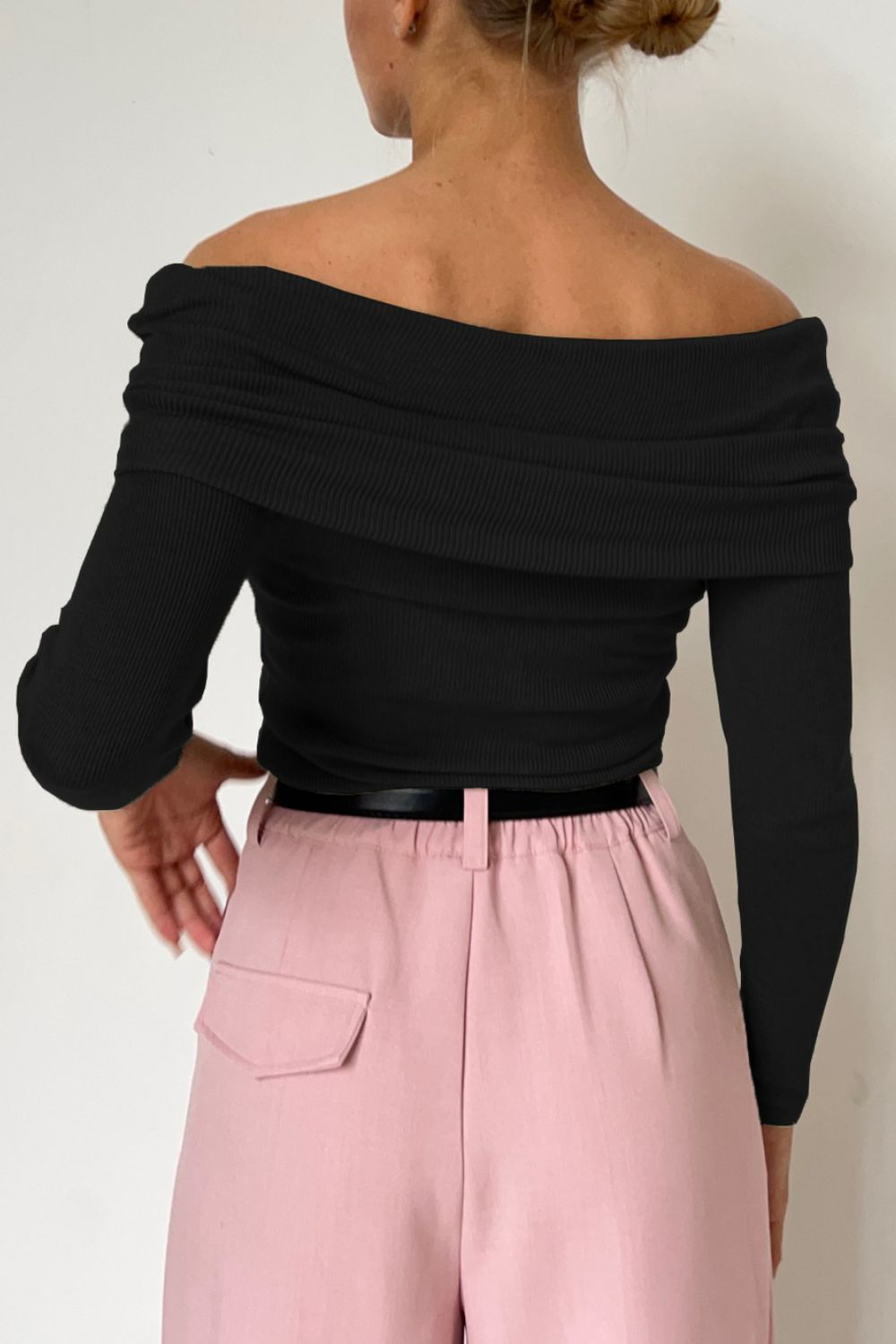 Black off-the-shoulder ribbed drape top with long sleeves.