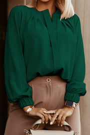 Green pleated yoke blouse with button detail and gathered cuffs.