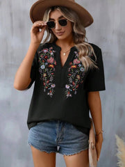 Black V-neck tunic with colorful floral embroidery and crochet trim detail.