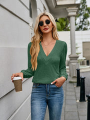 Dark green plunge neckline top with gathered sleeves and textured detail.