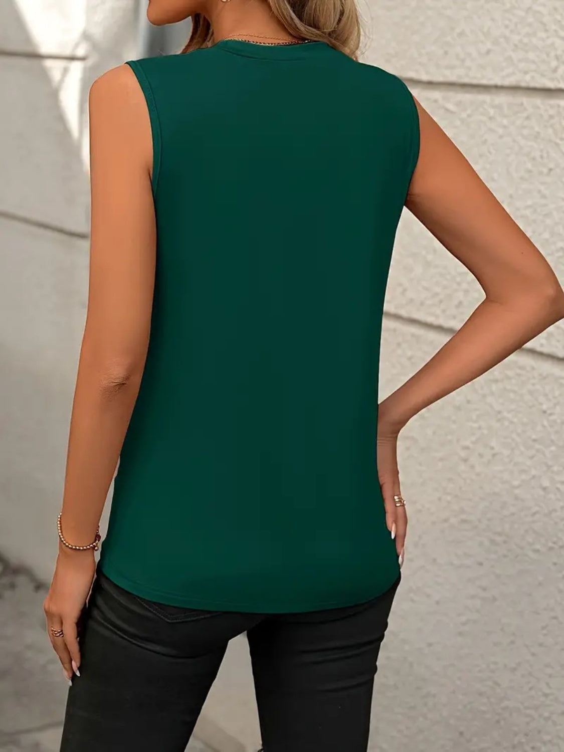 Sleeveless dark green tank top with diagonal seam detail, crew neck, and a relaxed fit.