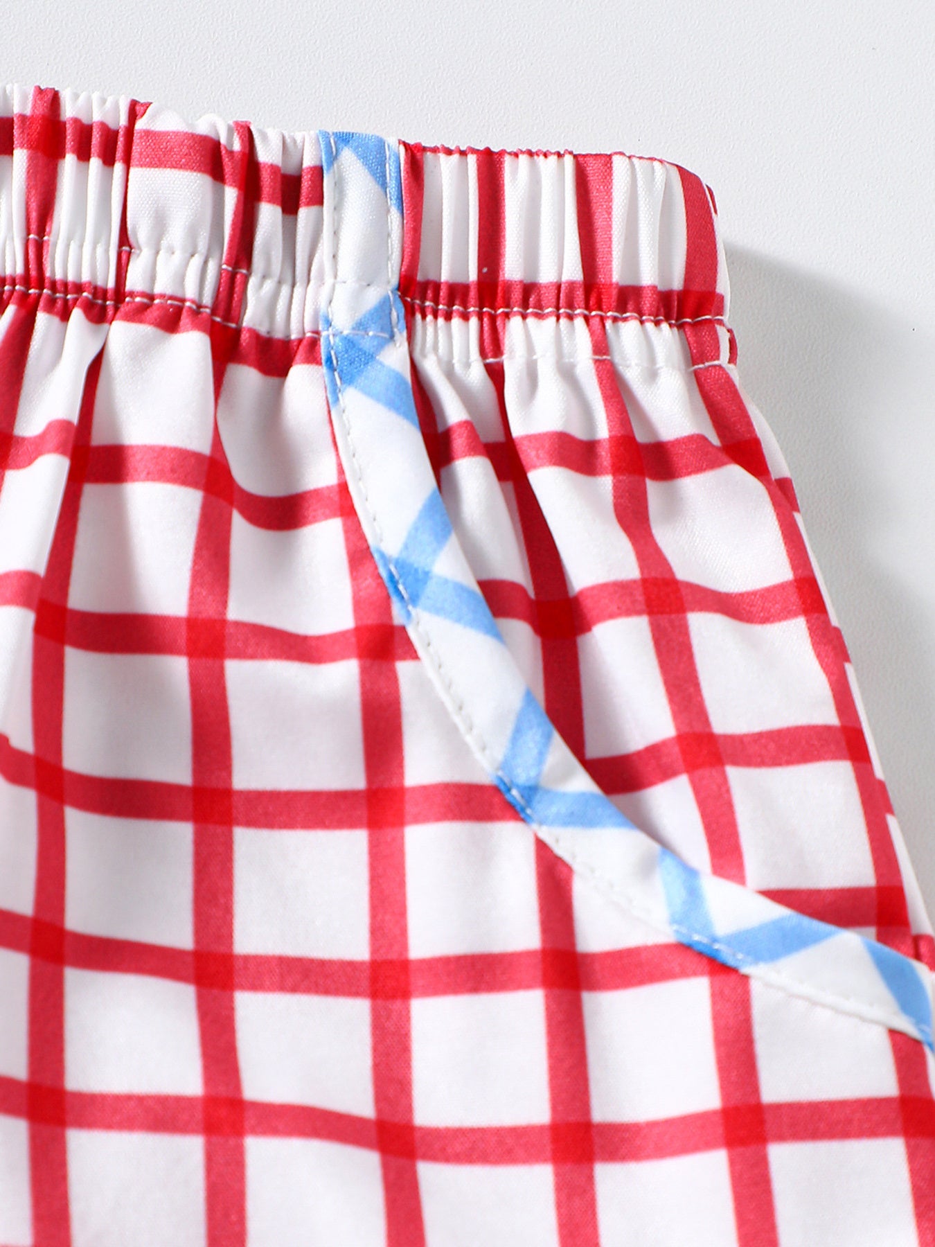 Baby shorts with red and white gingham pattern and blue trim detail