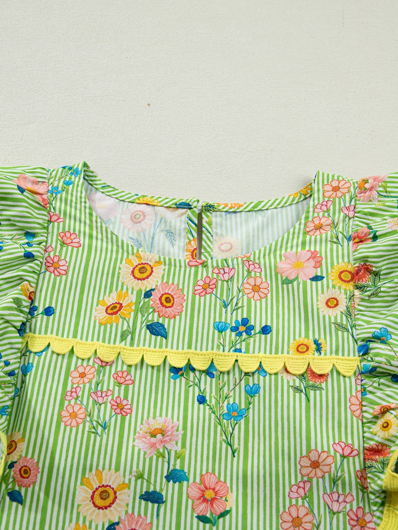 Green striped cotton blouse with floral print, ruffle sleeves, and yellow trim.