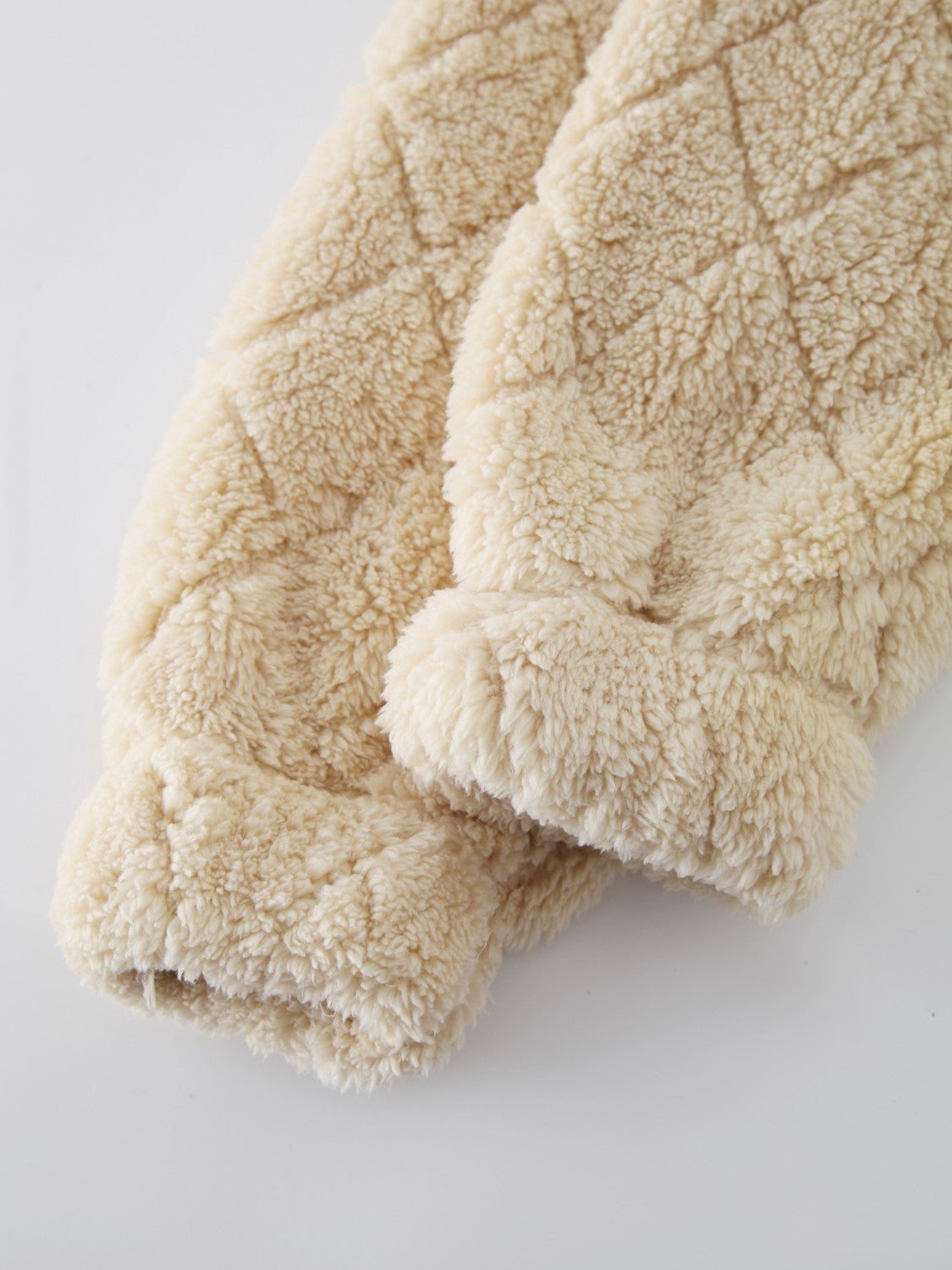 Textured teddy zip-up jacket in tan with diamond quilting and fuzzy cuffs.