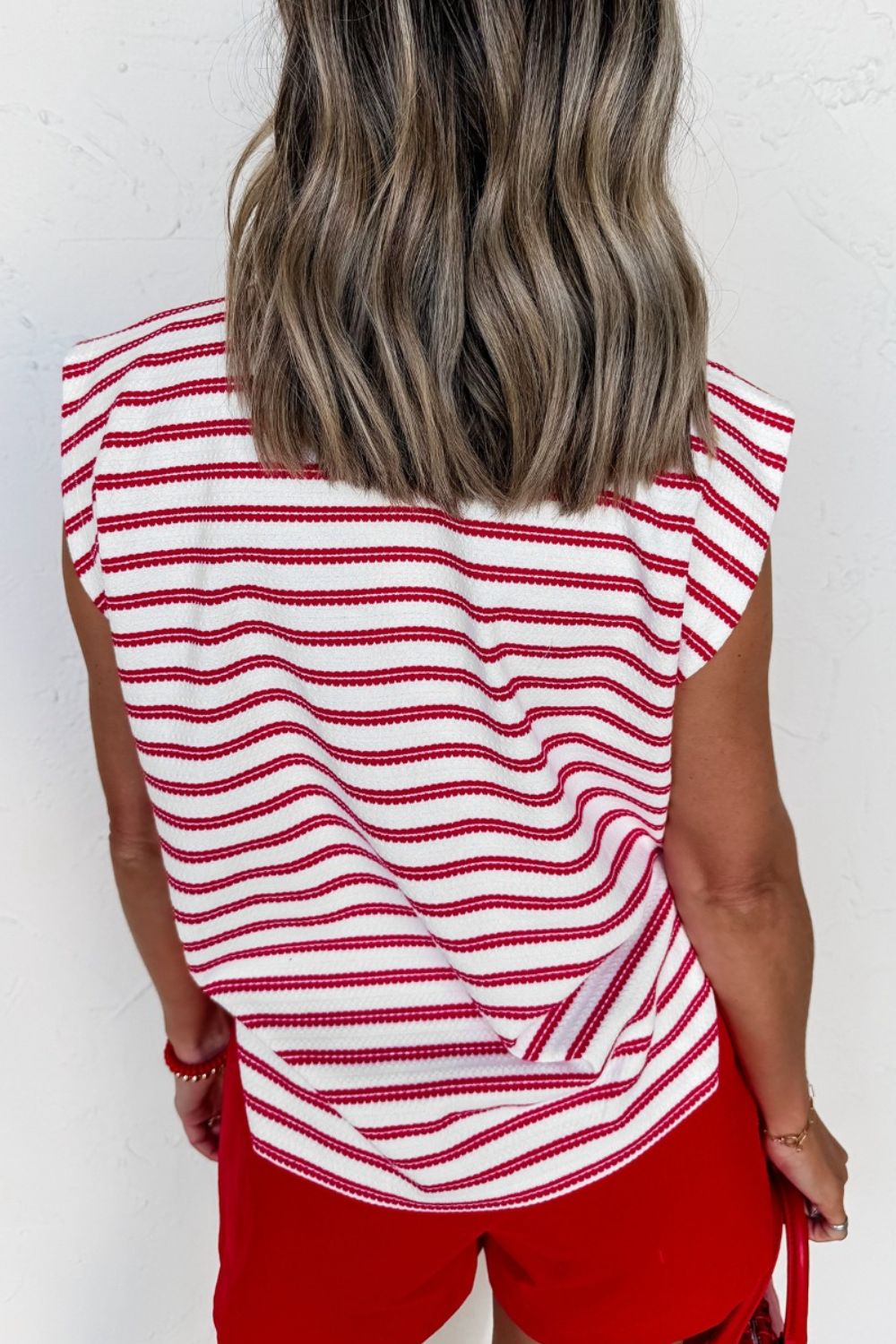 Textured knit tee with red and white stripes, crew neck, and decorative button detail.