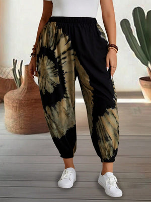 Tie-dye harem trousers with elastic waist in black and tan, featuring a relaxed fit and cuffed ankles.