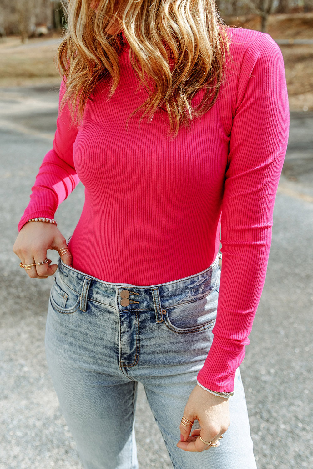 Hot pink ribbed turtleneck bodysuit with long sleeves styled with light wash jeans.