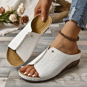 White crocodile-embossed wedge sandals with a slip-on design and gold stud detail.