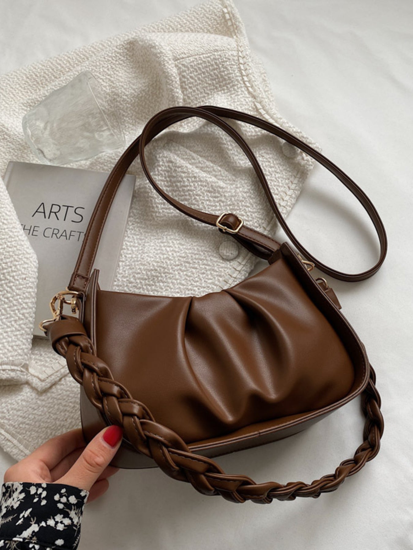 Brown ruched crossbody bag with a braided strap and adjustable shoulder strap.