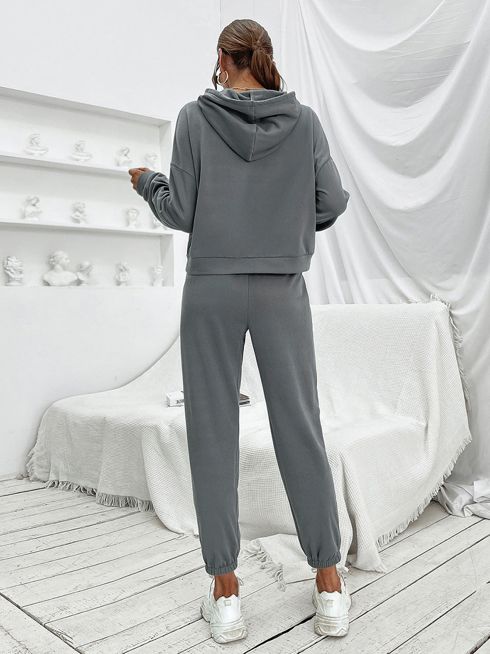 Dark gray cropped hoodie and joggers set with elastic cuffs, worn by a model.