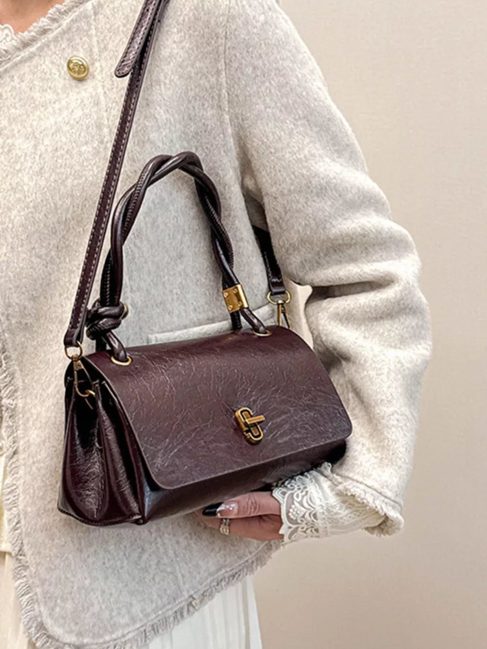 Chic crossbody bag in brown with twisted handle and gold clasp detail.