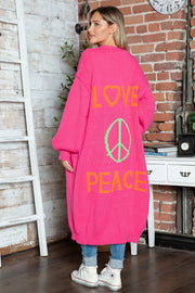 Pink knit maxi cardigan with "LOVE PEACE" and peace sign graphic, long sleeves.