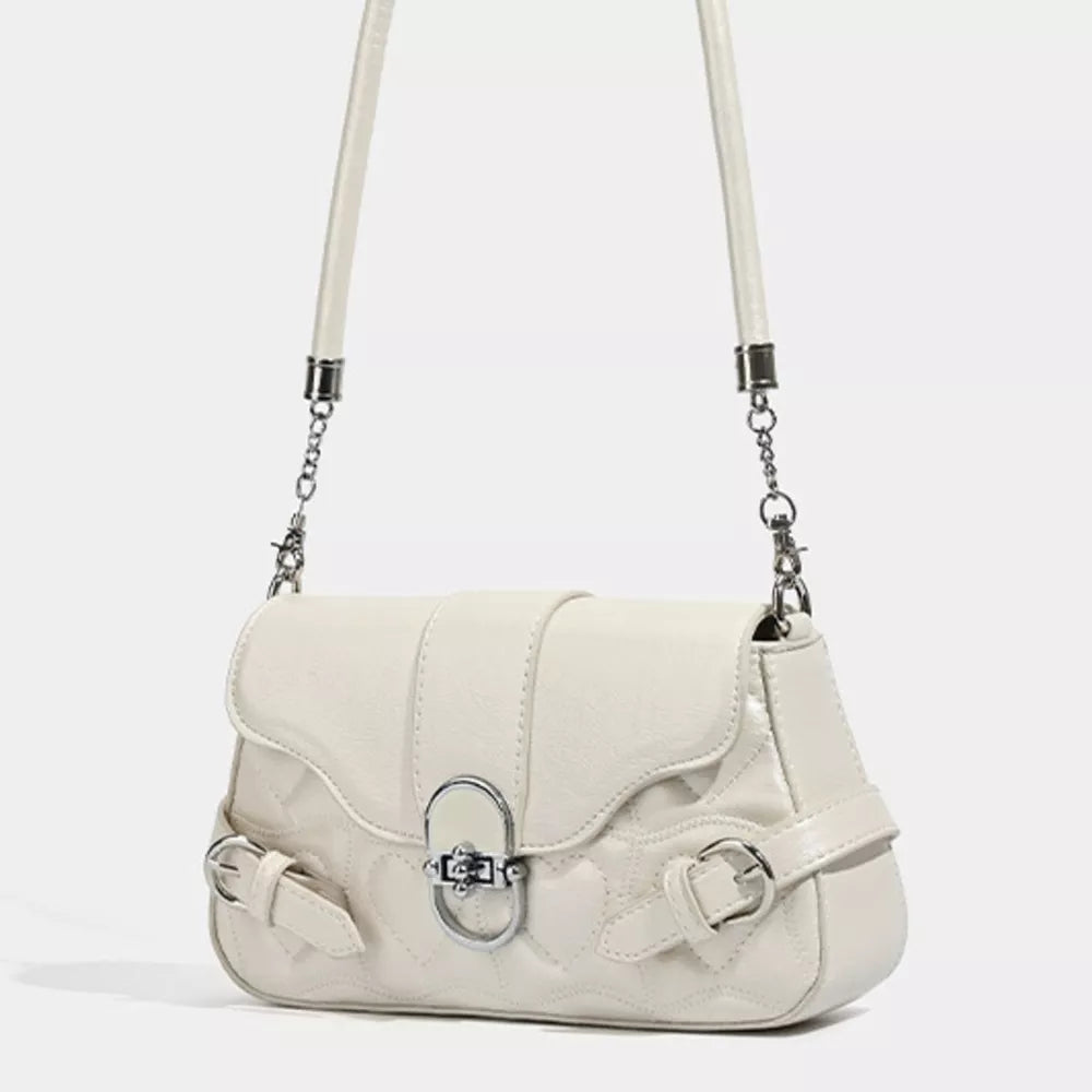 White heart-quilted crossbody bag with buckle accents and silver chain strap detail.
