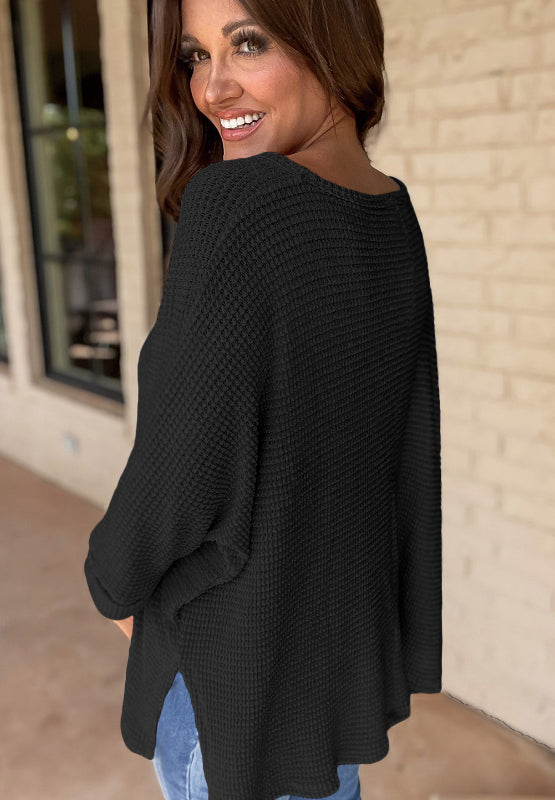 Black waffle knit V-neck sweater with slit hem and long sleeves.