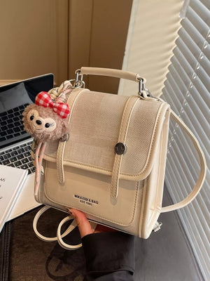 Chic mini flap backpack in cream with plush charm and red gingham bow.