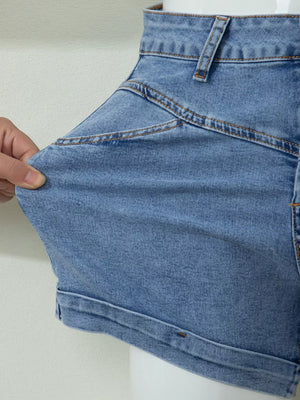 Blue cuffed denim shorts with high waist and angular seam detail.