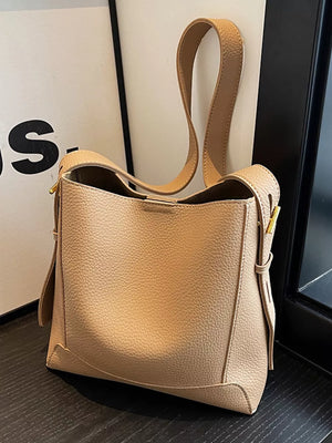 Khaki pebbled leather crossbody bag with adjustable strap and gold hardware detail.