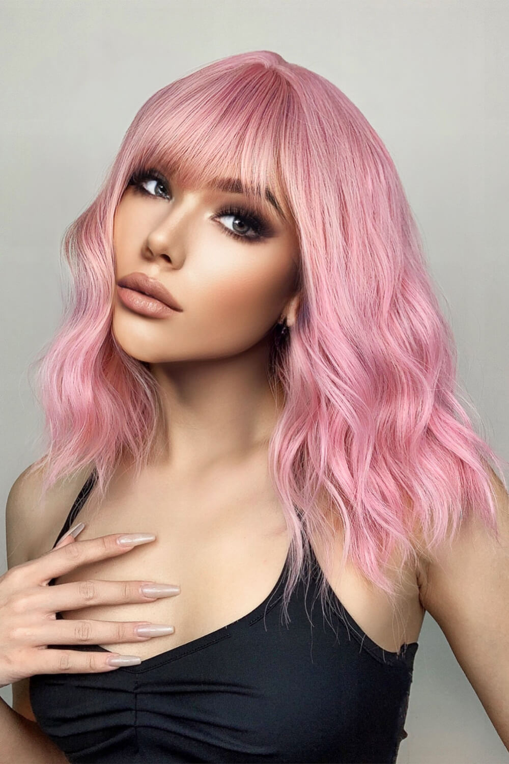 Pink bob wig with bangs and wavy texture, styled on a model.
