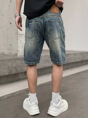 Men's blue distressed denim shorts with patchwork details and a leather patch.