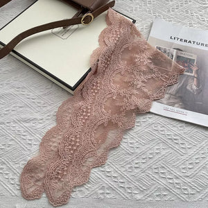 Delicate pink floral lace scarf with scalloped edges.